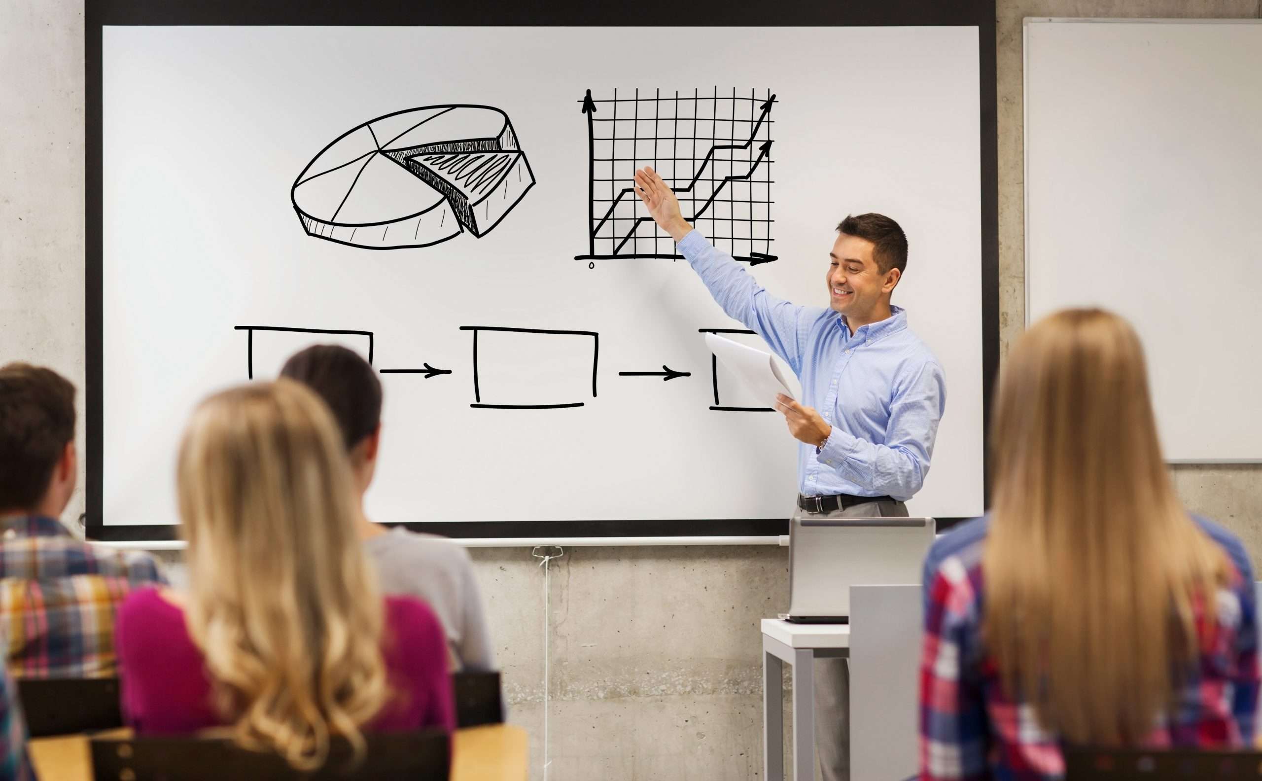 education high school teaching economics people concept group students happy teacher with notepad showing scheme white board classroom scaled