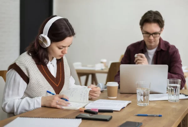 girl-with-headphones-using-laptop-along-her-classmates-group-study